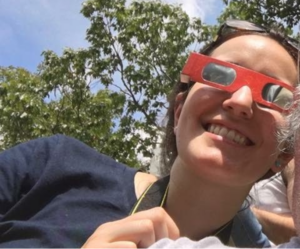 Woman in red solar eclipse glasses.