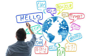 Man drawing on white board featuring a globe and speech bubbles saying hello in multiple world languages.