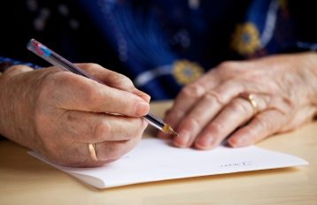 Elderly person's hands writing a letter