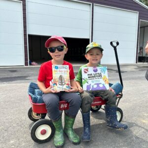 Two boys holding books sitting in a wagon