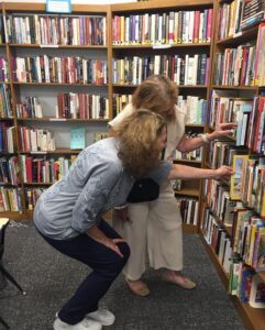 two women looking at bookshelf.