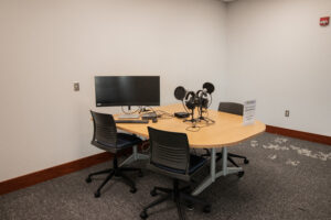 Table with chairs, computer monitor, and audio recording equipment