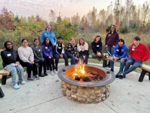 Group of teens gathered around a fire pit