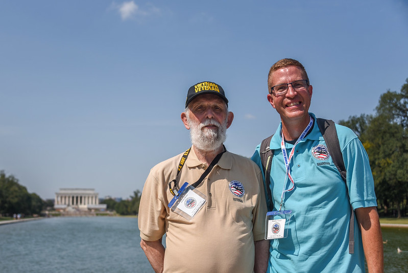 Two men posing in front of war memorial