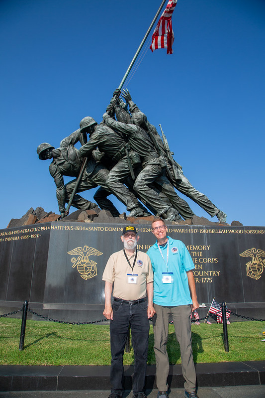 Two men posing in front of war memorial