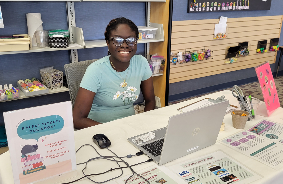 woman smiling at a desk with a computer