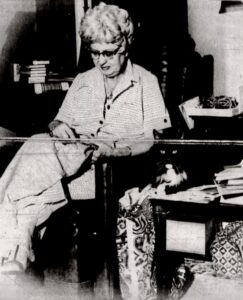 Photo of Audrey Haworth taken from the Daily Ledger, accompanied by the caption, “Miss Haworth completes her latest project, a design in crewel as Pixie, one of her three pet cats, rests nearby. Sewing, knitting, and adding to her collection of more than 300 glass, wooden, and ceramic cat figurines, occupies much of her leisure time since retirement."