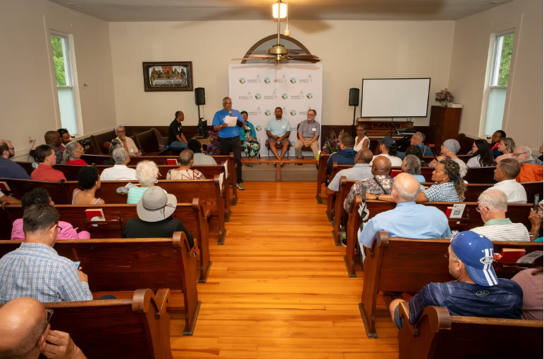 Image of gathering with three people on stage and the rest in pews