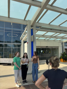 four women filming a video in front of library