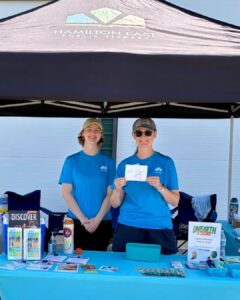 Two women in blue shirts under tent