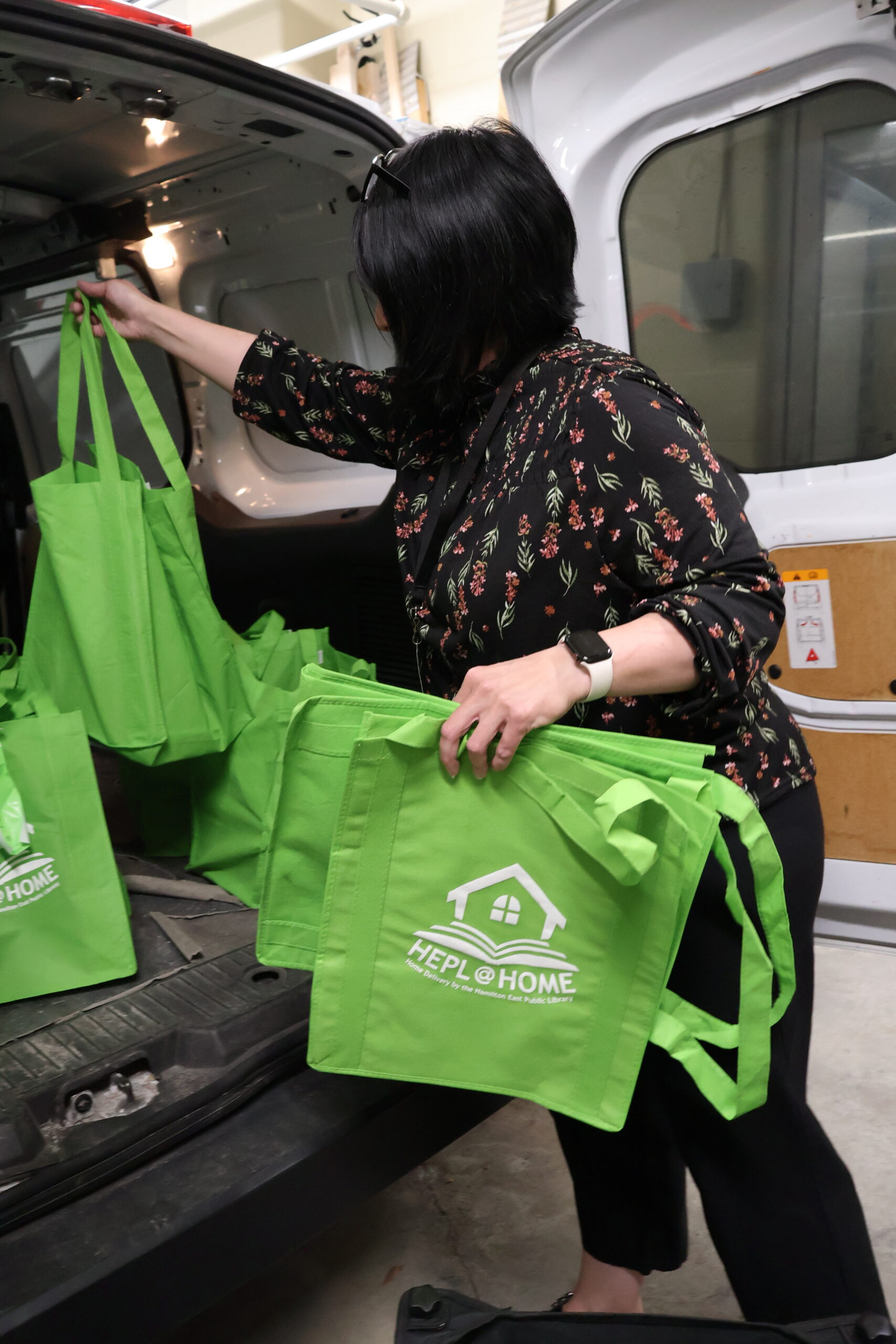 woman loading green home delivery bags into van