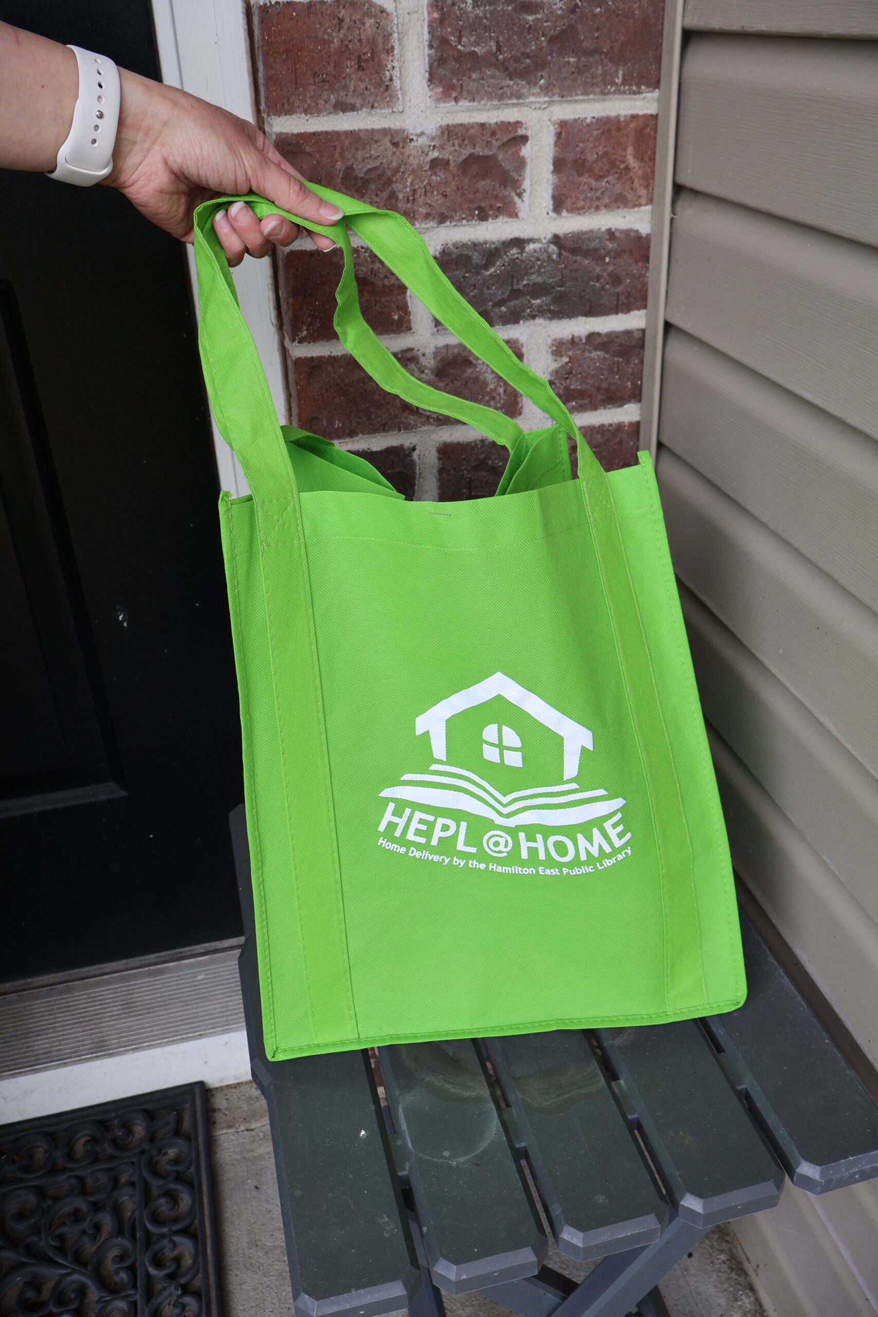 hand holding green home delivery bag