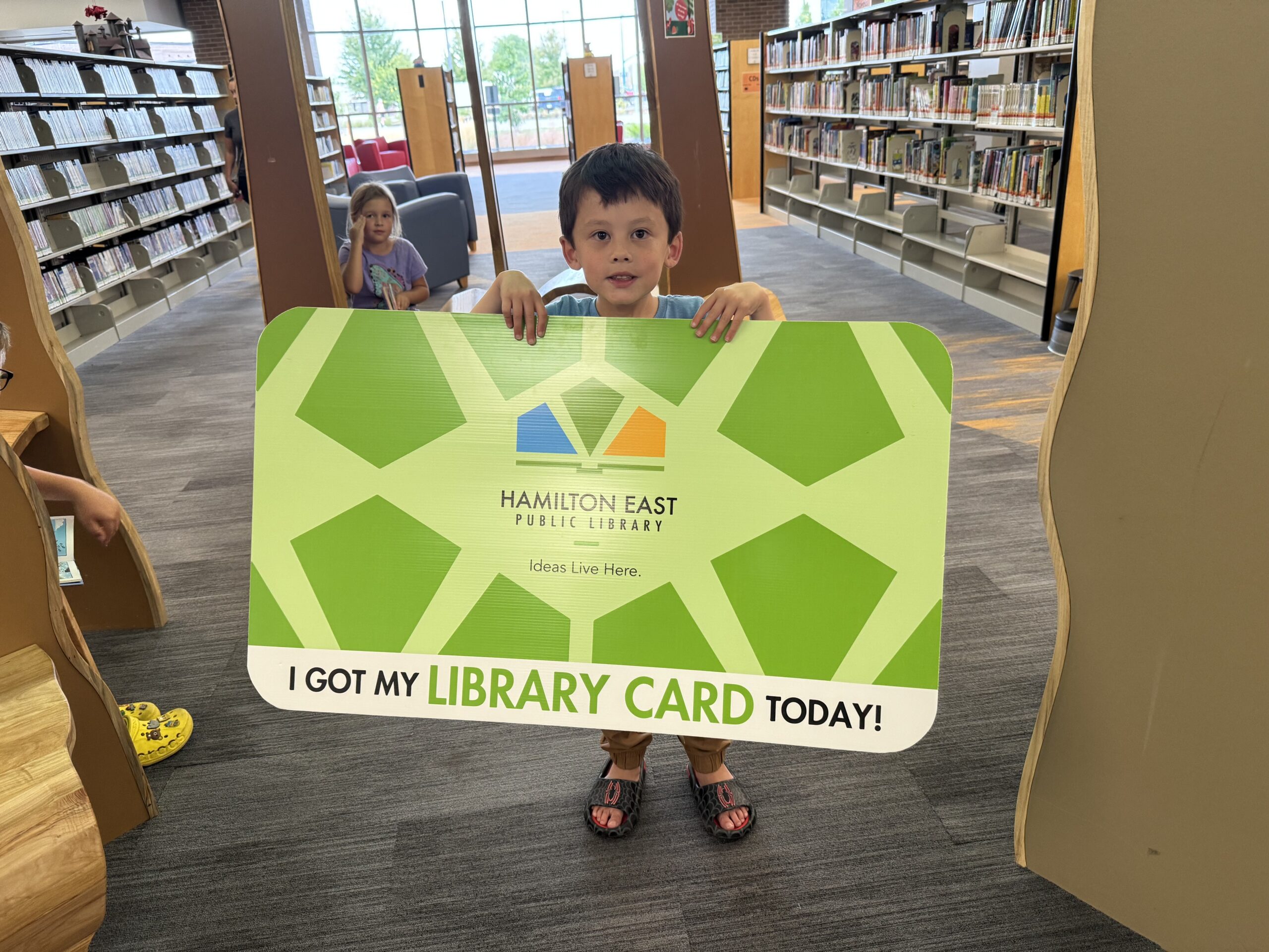 Boy holding giant green library card that says 